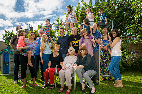 Portrait of large family group in garden on climbing frame