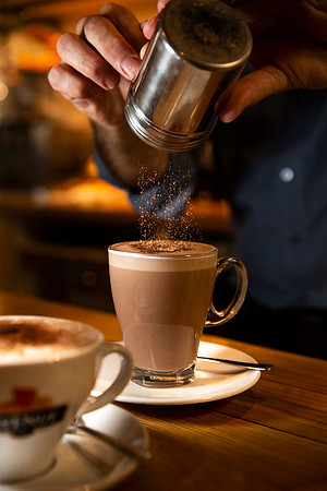 Sprinkling cocoa powder on coffee at the Avenue Cafe Bristol