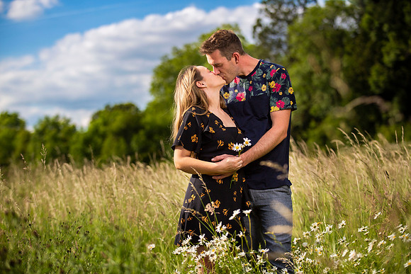 Portrait of couple kissing in fields with blue skies