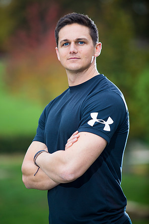 Outdoor portrait profile of personal trainer in park with autumnal colours on trees