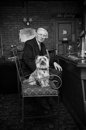 Old man in pub with dog sitting on chair